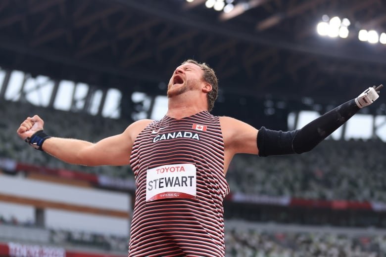 A Paralympic men's shot put athlete reaches his arms out while yelling in celebration.