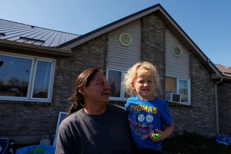 Jason Plain holds his grandson Teo before leaving with his family members during a voluntary evacuation of the Aamjiwnaang First Nation, near Sarnia, Ont., on Oct. 1, 2024. The nearby Ineos Styrolution plant is removing benzene from a storage tank as part of the plant’s dissolution.