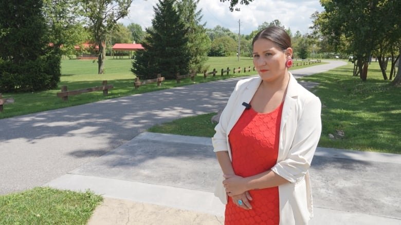 a woman in a red dress stands in front of a green field