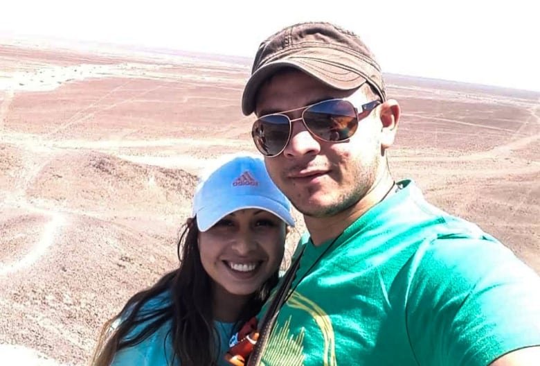 A man and woman wearing ball caps smile as they take a selfie.