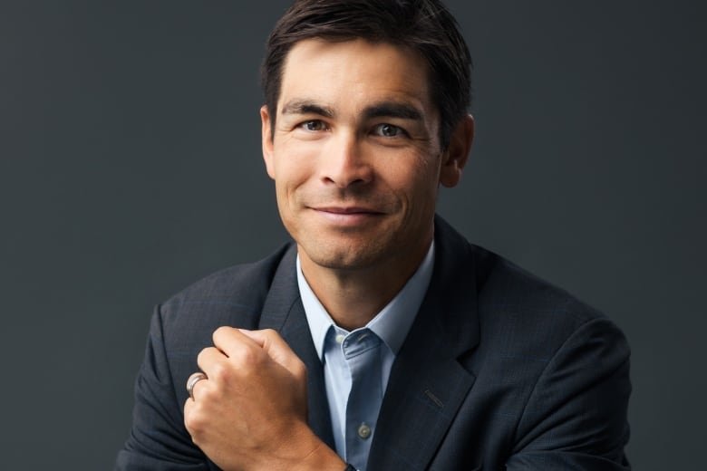 A man in a suit smiles and raises his fist.