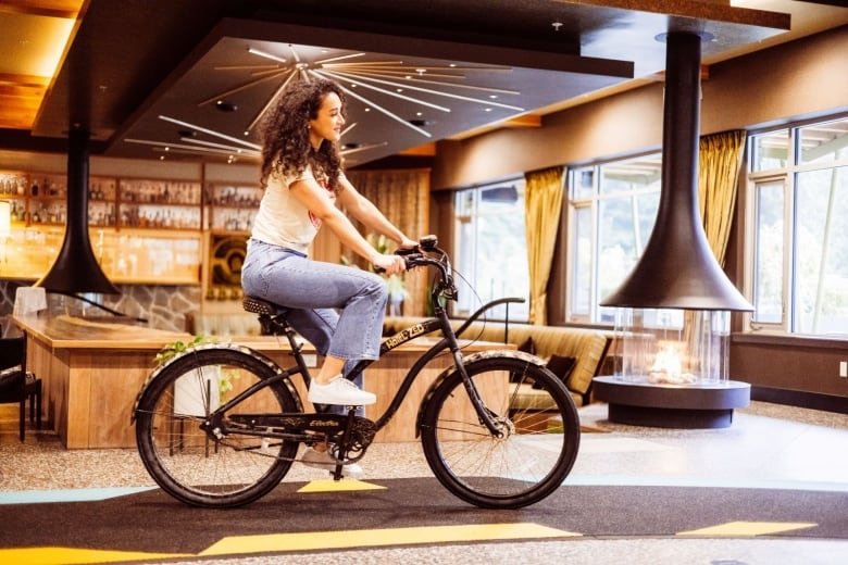 A woman rides a bicycle through a paved path that runs through the interior of a hotel lobby.