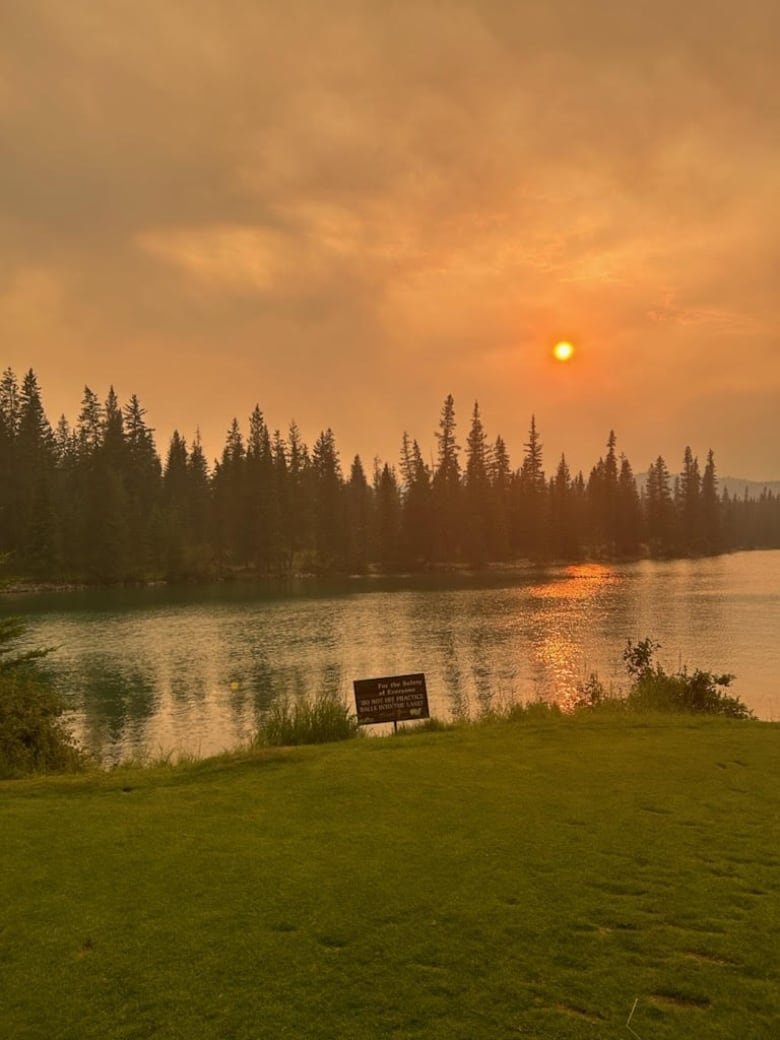 A lake with forest in the background at sunset.