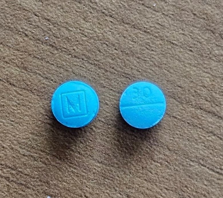 Two blue pills on a table.