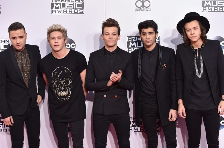 Five people pose for photographs at a red carpet.