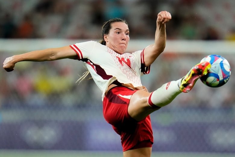 A woman soccer player kicks the ball.