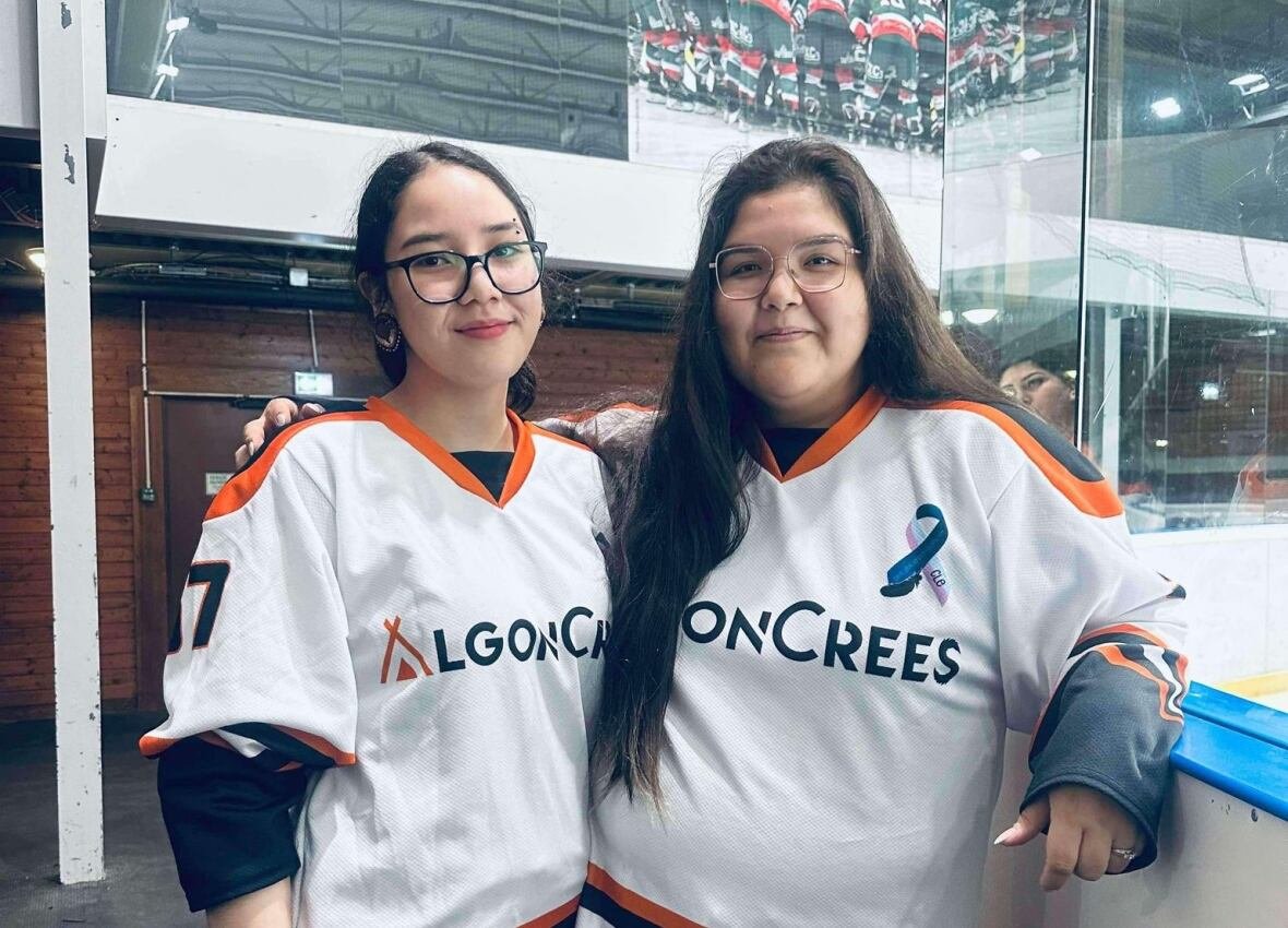 Two women standing beside an ice rink.