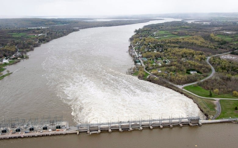 A dam is shown on a wide river on a cloudy day.