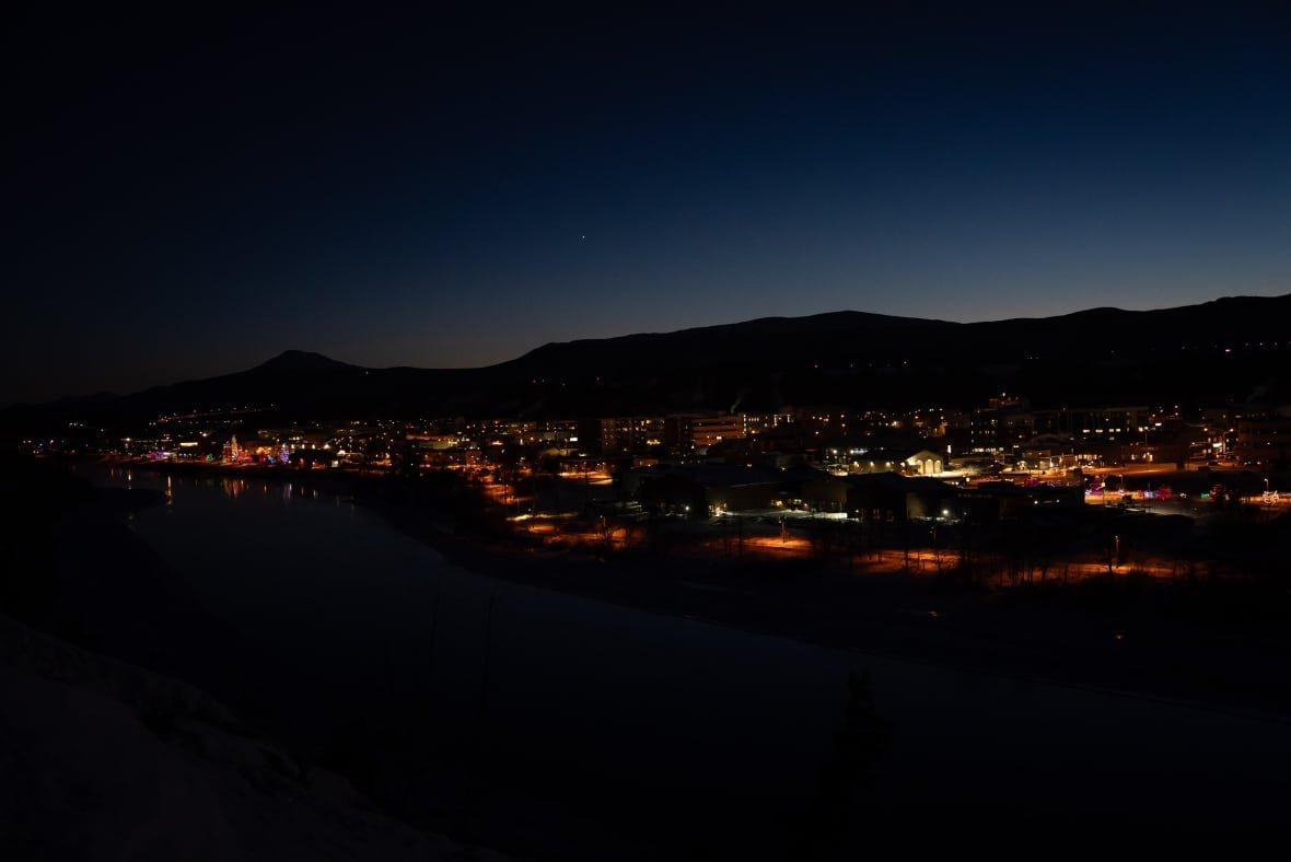 The photo shows a city still in the darkest of the matinee, some buildings and streetlights shining.