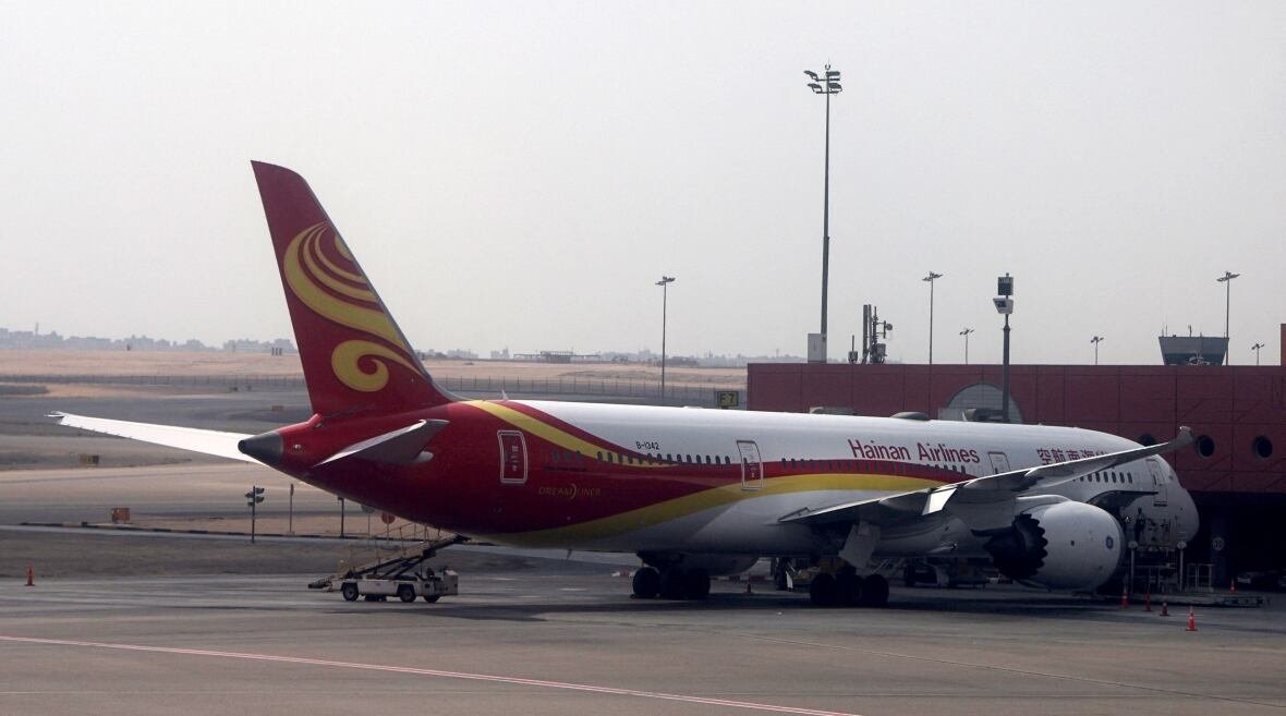 A large airplane sits on the tarmac outside of a building.