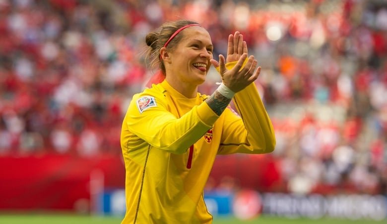 A women's soccer goalkeeper salutes fans.