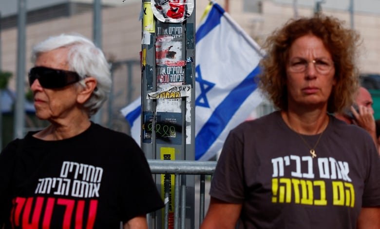 Two people stand side by side in a crowd. They're both wearing T-shirts with Hebrew lettering on them.