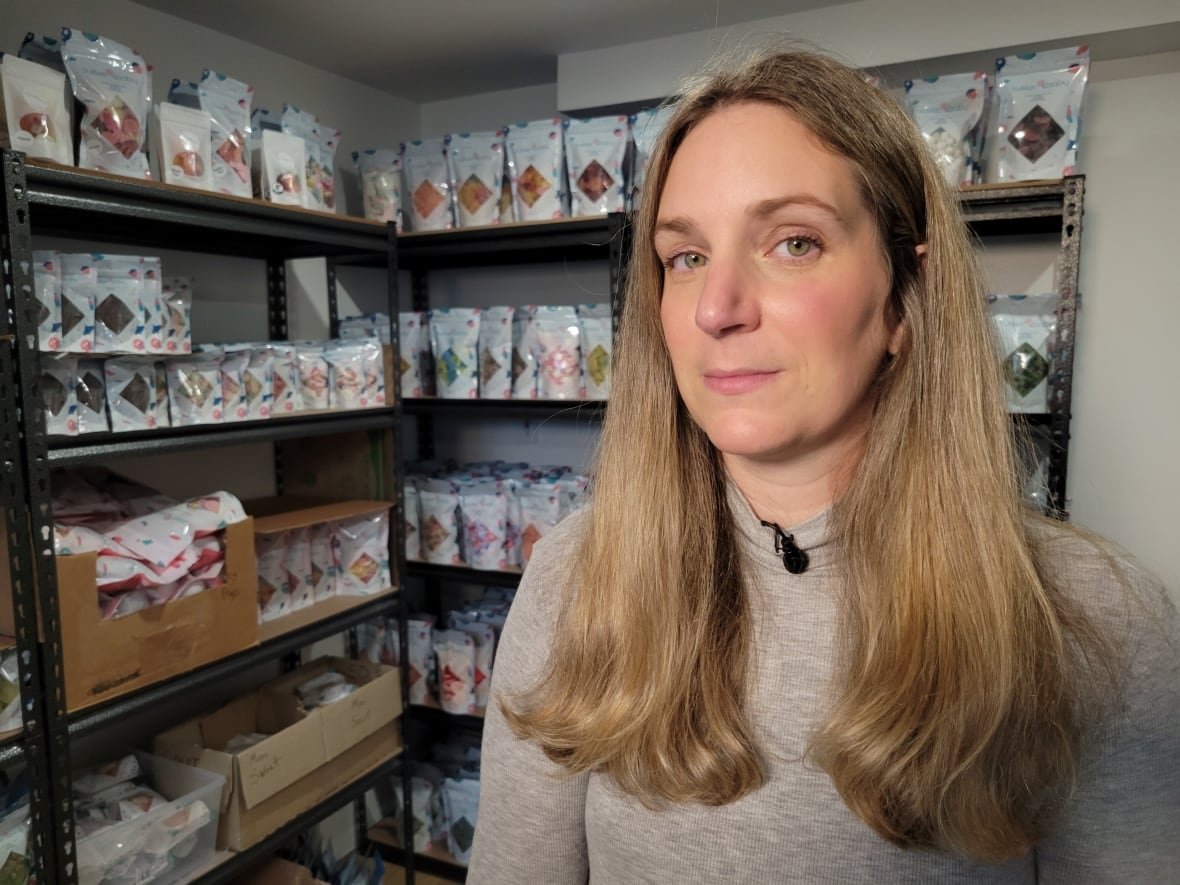 A woman is shown in a room where bags of candy line shelves.