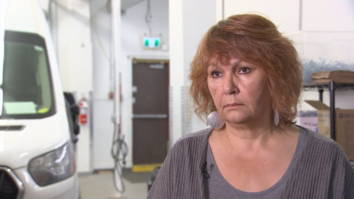 A woman with short brown hair stands in a warehouse.