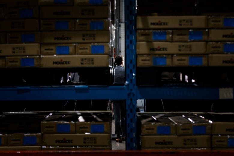 A man is just visible behind a rack of batteries in a factory.