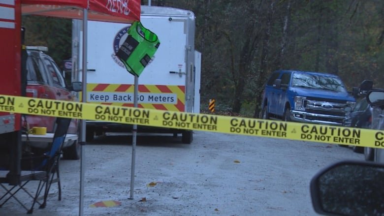 Emergency vehicles and tape are pictured on a cloudy day.