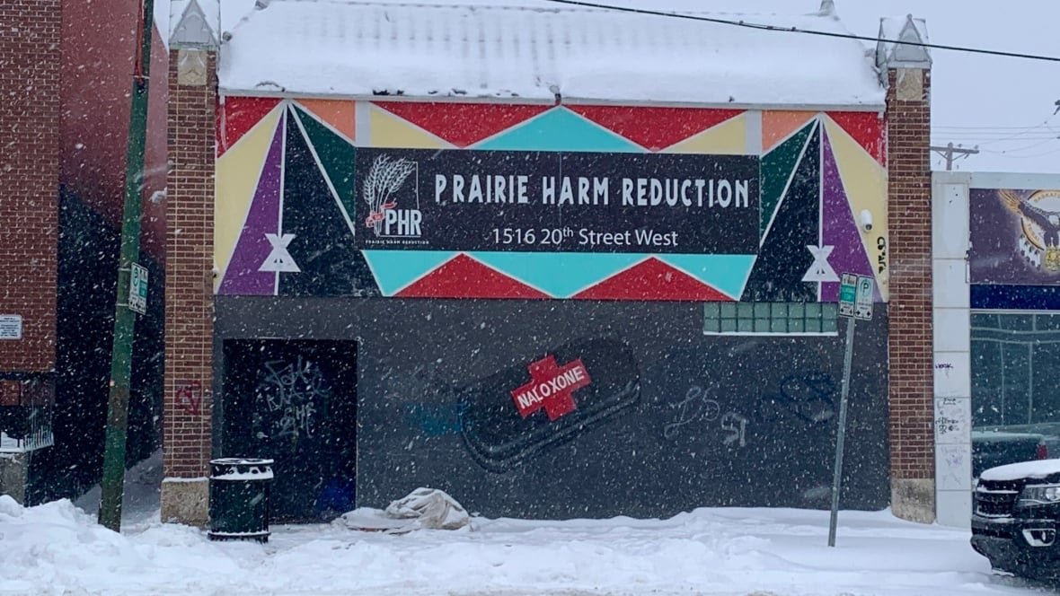 Snow falling on building with Prairie Harm Reduction sign.