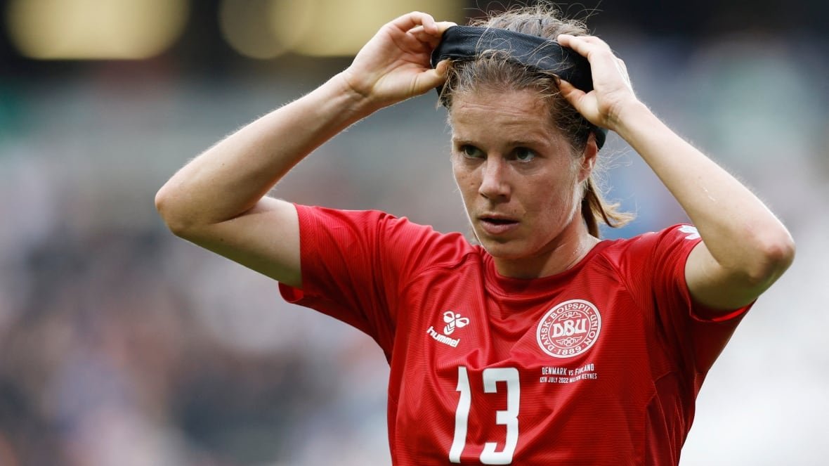 A soccer player adjusts her headband