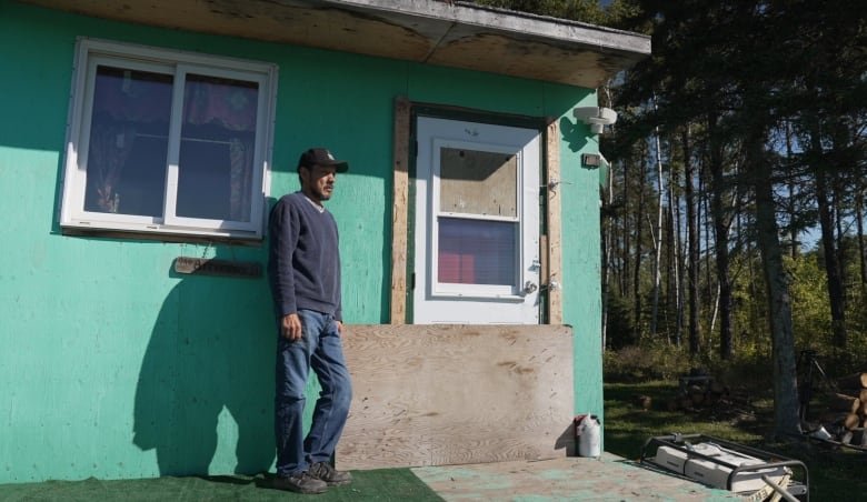 A man stands outside a backcountry cabin.