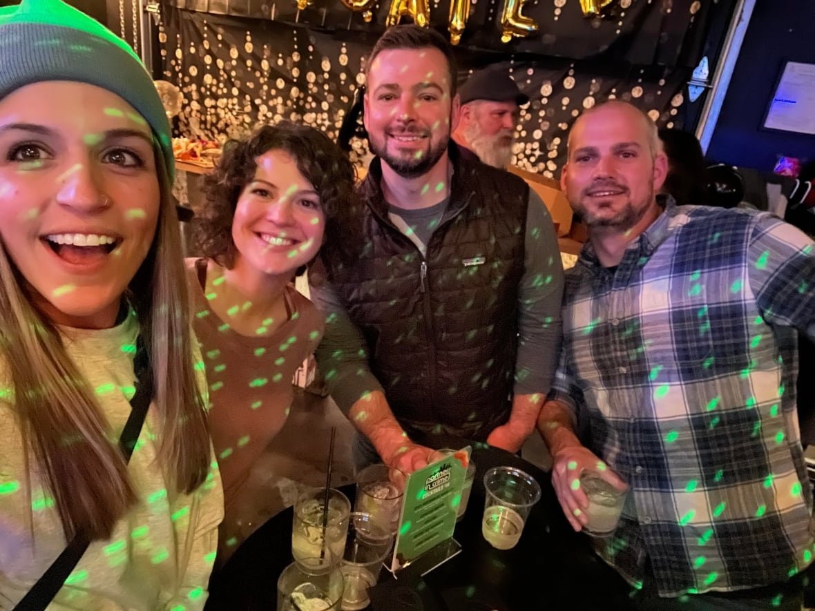 A selfie of four smiling people in a bar.