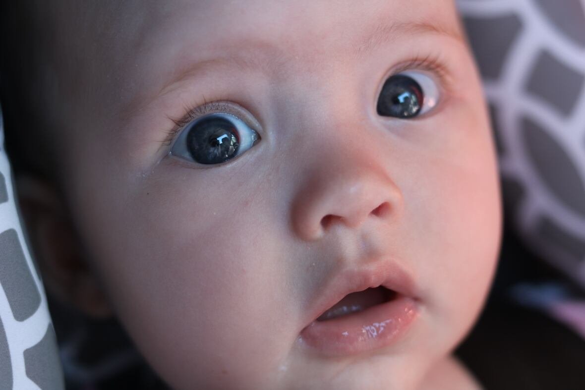 A baby looks into the camera.