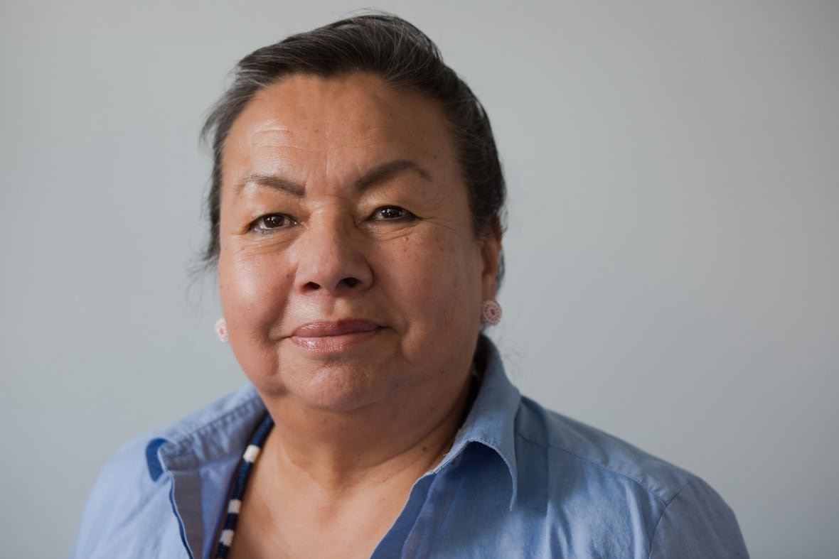 A headshot of a person wearing a blue-collared shirt.