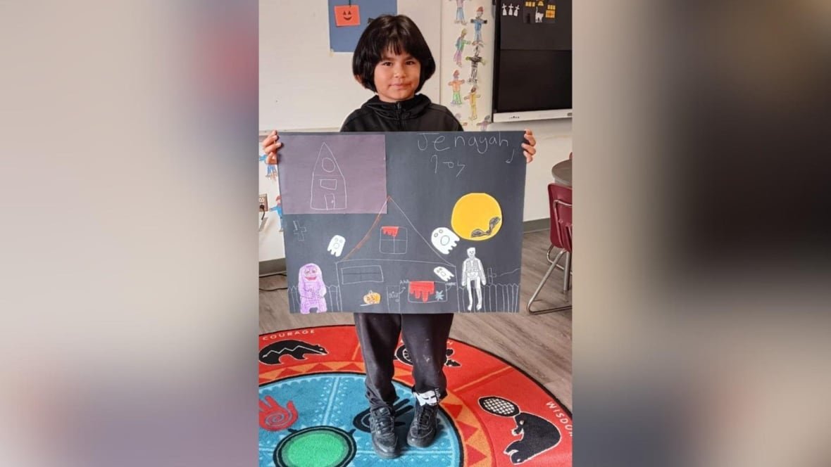 A child is seen holding up a poster in a classroom.