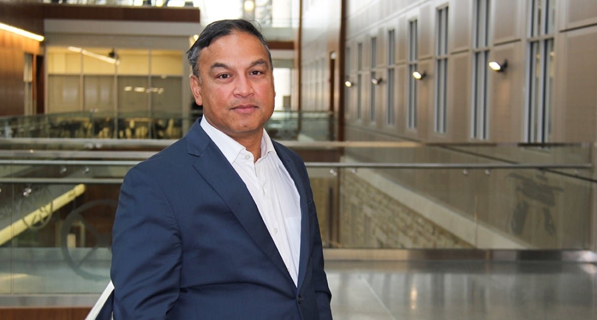 A man in a suit poses in a university building.