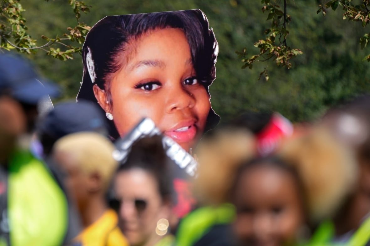 An image of a woman on a protest sign rises above a crowd