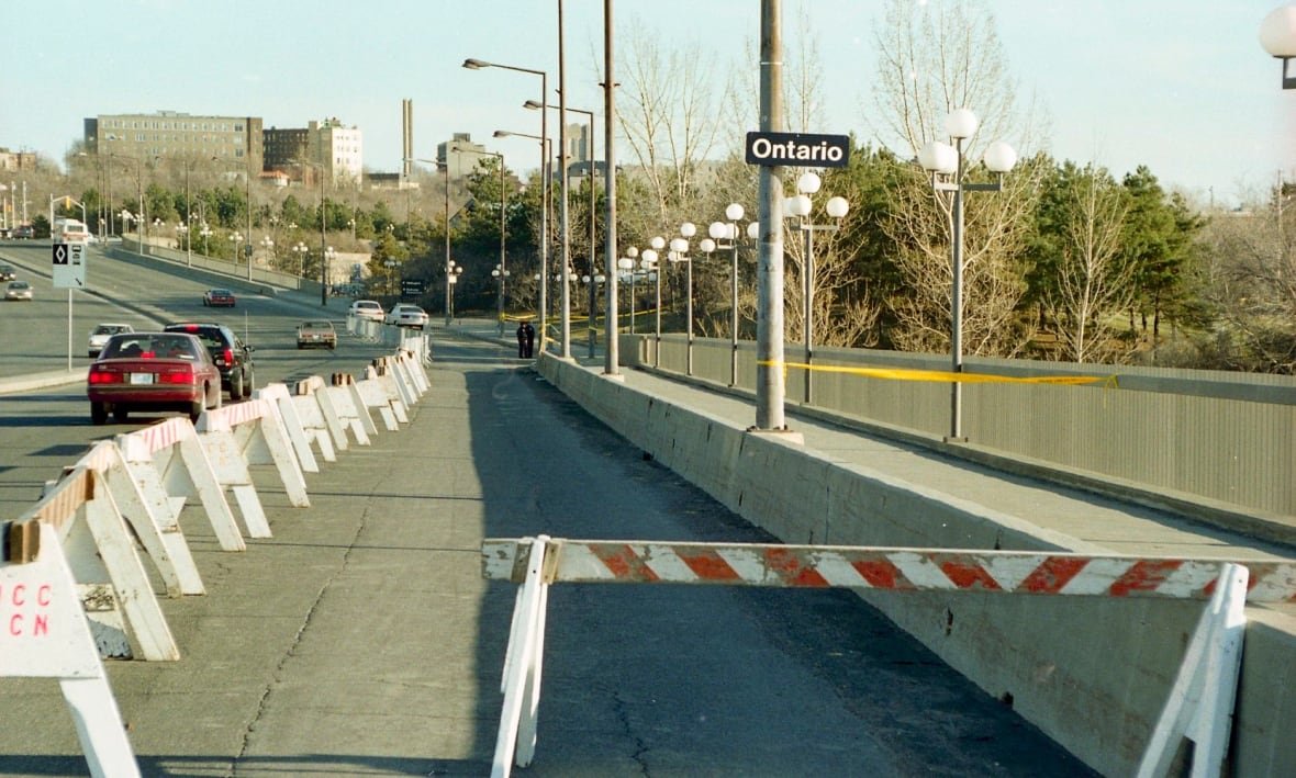 An old photo of a bridge with crime scene tape around a portion of it near a road sign that says Ontario.