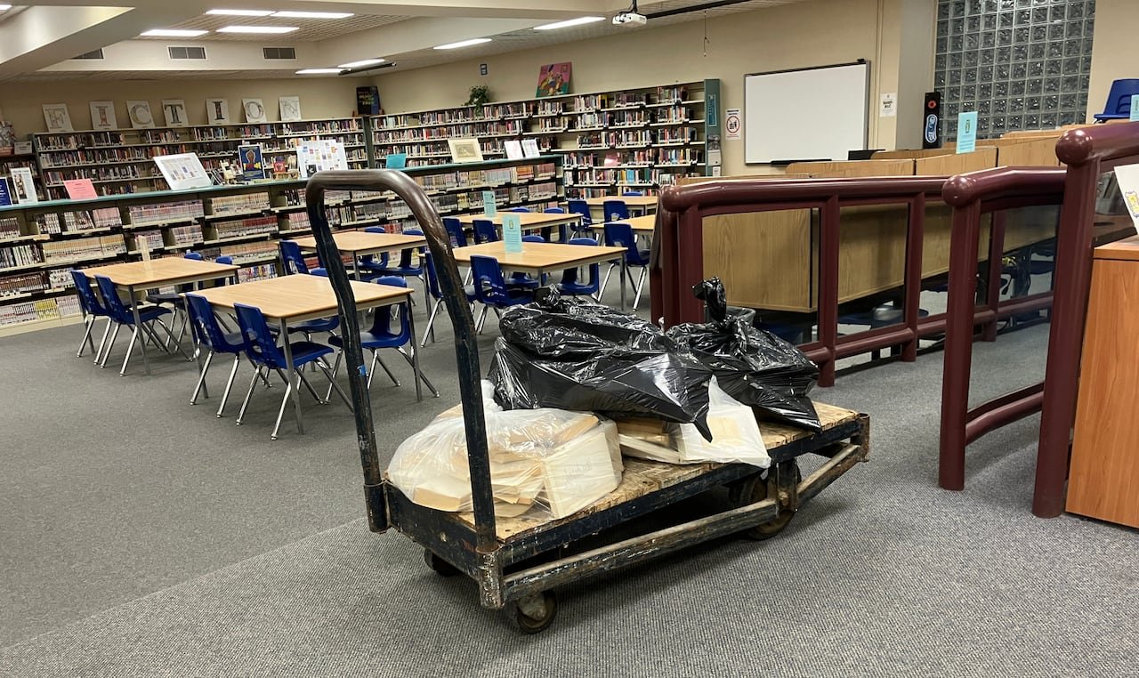 A cart filled with books in plastic bags at a library