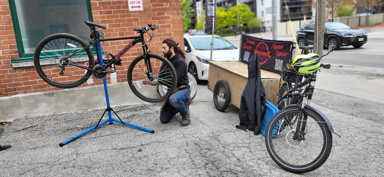 default-159 Man repairing a bicycle beside an e-bike with a trailer